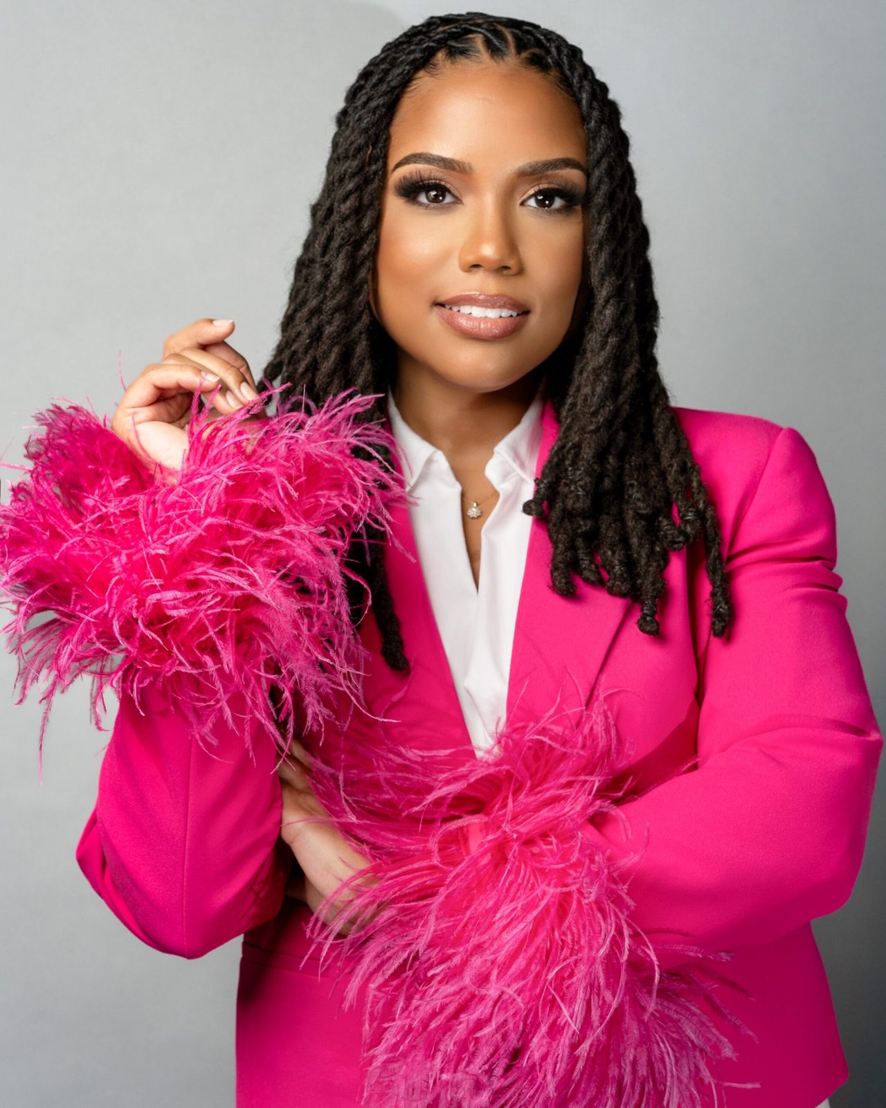 Founder in a hot pink blazer with feather trim photographed in studio