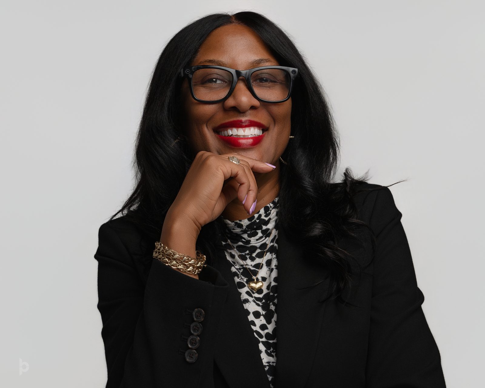 Executive in glasses and a black blazer smiling in a studio portrait